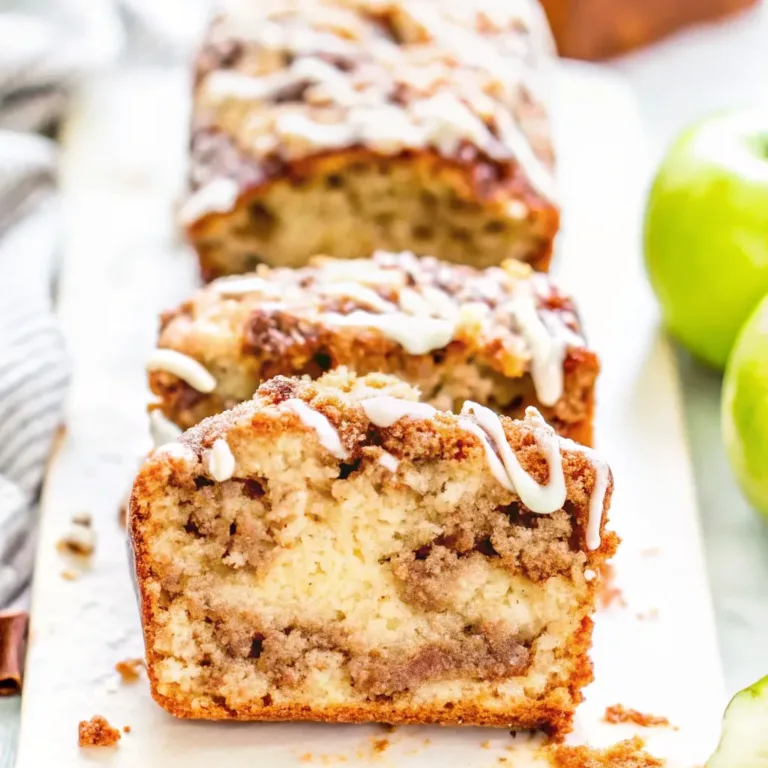 A close-up of a thick slice of moist Amish Apple Fritter Bread, showing the gooey cinnamon swirl inside and a sweet vanilla glaze drizzled on top.
