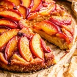 Bourbon Peach Upside Down Cake Bourbon Peach Upside Down Cake A rustic Bourbon Peach Upside Down Cake with caramelized peach slices, sitting on brown parchment paper with one slice removed to show the moist cake inside.