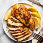 Air Fryer Chicken Breast : The Last Juicy Recipe You’ll Ever Need Air Fryer Chicken Breast Sliced and whole juicy air fryer chicken breast on a white plate with lemon wedges and herbs