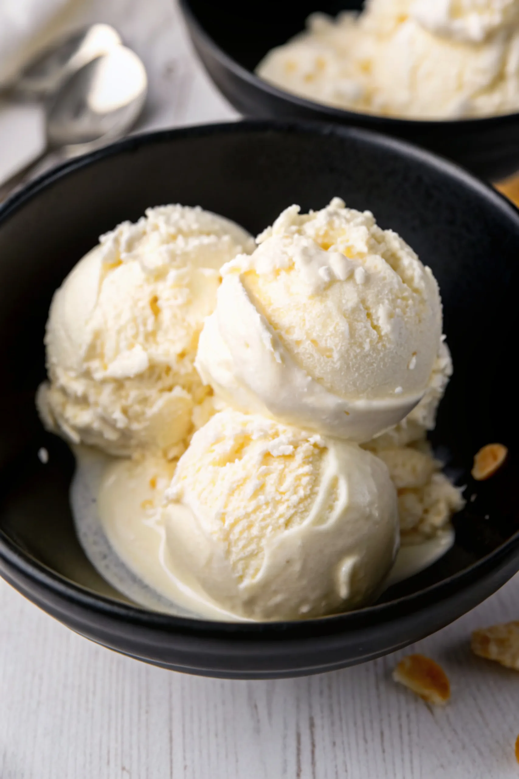 Three scoops of creamy homemade pinon ice cream in a black bowl.