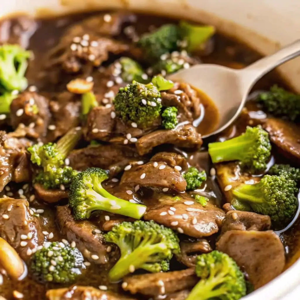 How to Cook Beef and Broccoli Chinese Style That Beats Takeout how to cook beef and broccoli chinese Spoon scooping beef and broccoli in thick sauce with sesame seeds