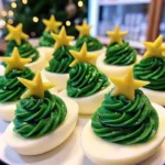 Festive deviled eggs decorated as Christmas trees with green filling and star toppers