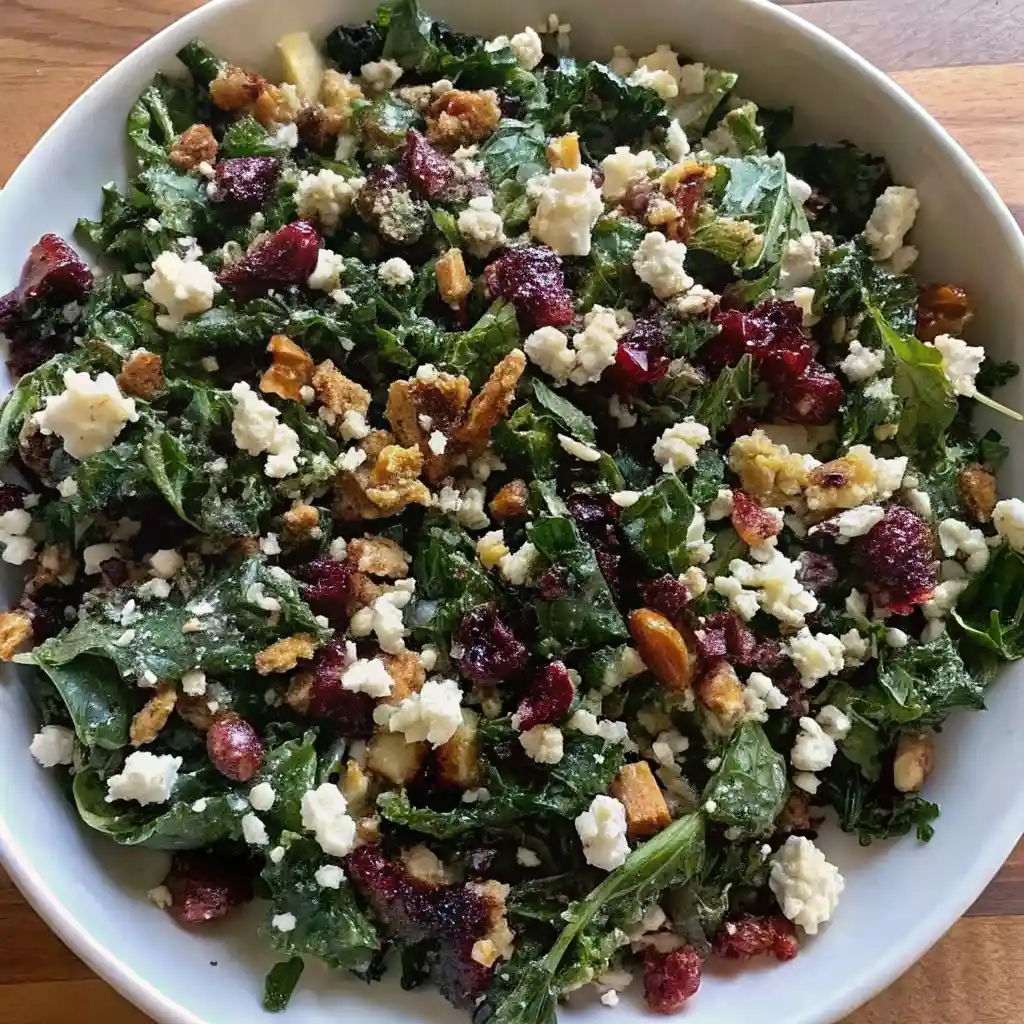 Kale Salad Recipe – Fresh, Crunchy & Easy to Make Kale Salad Fresh kale salad topped with feta cheese, dried cranberries, nuts, and crunchy toppings in a white bowl.