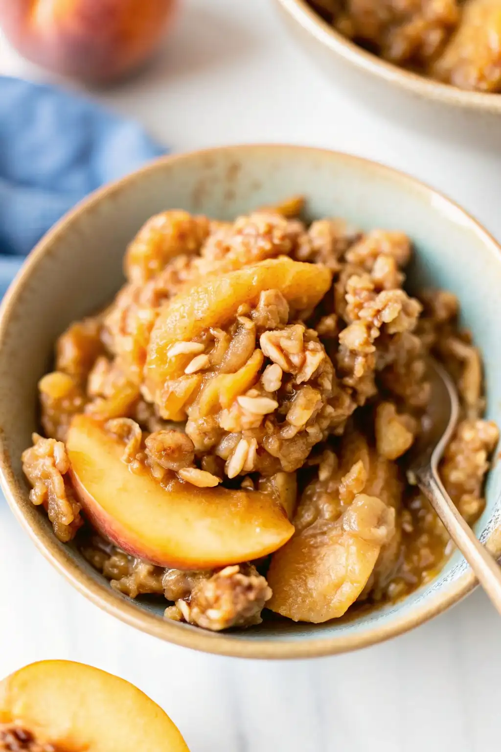 Homemade peach crisp with juicy peach slices and a golden oat topping served in a bowl.