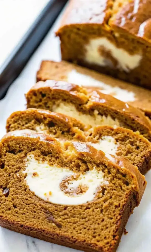 Pumpkin Cream Cheese Bread Pumpkin Cream Cheese Bread Freshly baked pumpkin cream cheese bread sliced to reveal a creamy swirl center on a marble surface