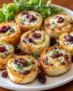 Savory Christmas cranberry roll ups with cream cheese, herbs, and cranberries on a white platter