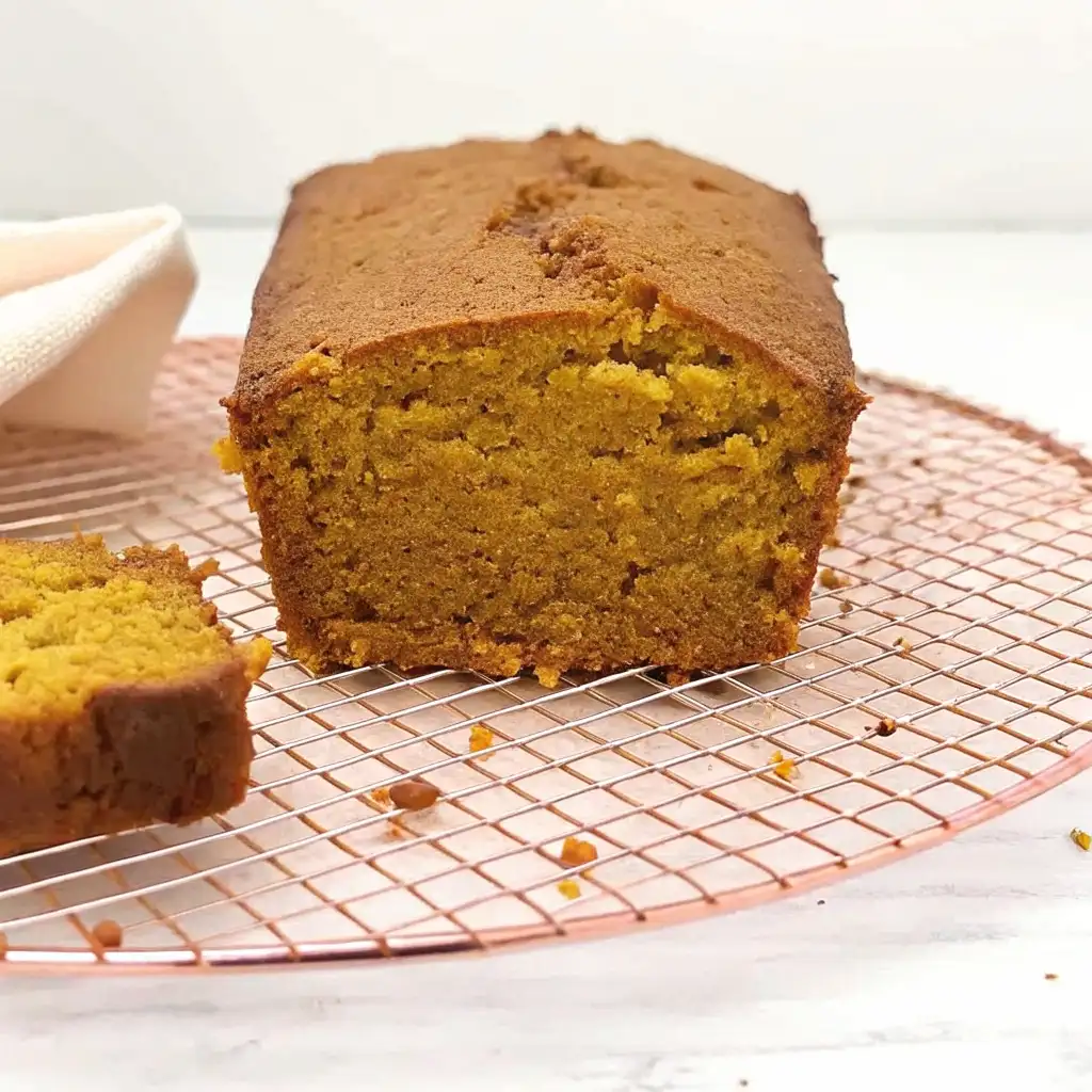 Super Moist Pumpkin Bread with Cream Cheese Frosting Super Moist Pumpkin Bread Freshly baked pumpkin bread loaf cooling on a wire rack, showing its golden moist interior and rich brown crust.