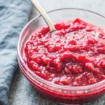 Keto cranberry sauce recipe in a glass bowl with spoon