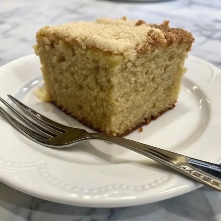 A perfect slice of cowboy cake on a white plate, showing the fluffy inside and the crunchy cinnamon crumb topping.