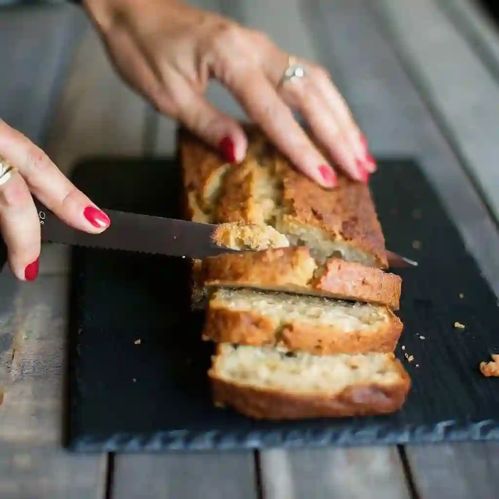 Best Ever Sour Cream Banana Bread Recipe – Moist & Easy Sour cream banana bread Homemade sour cream banana bread being sliced on a cutting board, soft and fluffy texture inside.