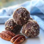 Homemade chocolate date energy balls displayed on a rustic wooden table.